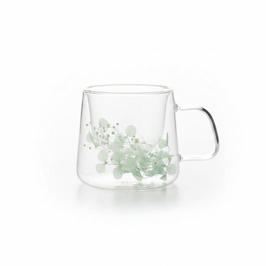 taza de vidrio con flores celestes para infusión